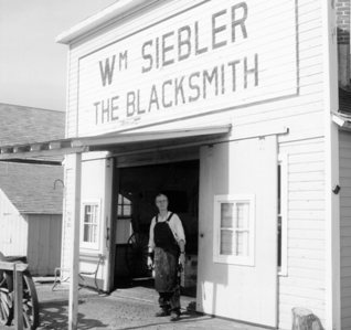 Ron Siebler stands in front of his Great Grandfather's blacksmith shop.